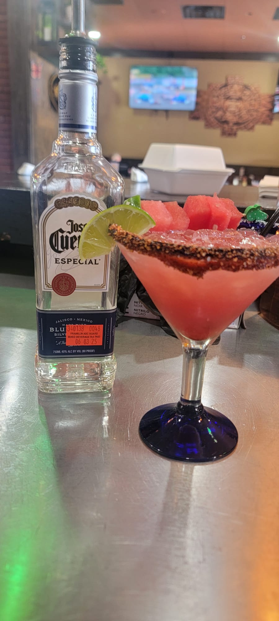 Watermelon margarita with chamoy rim topped with fresh watermelon chunks and lime