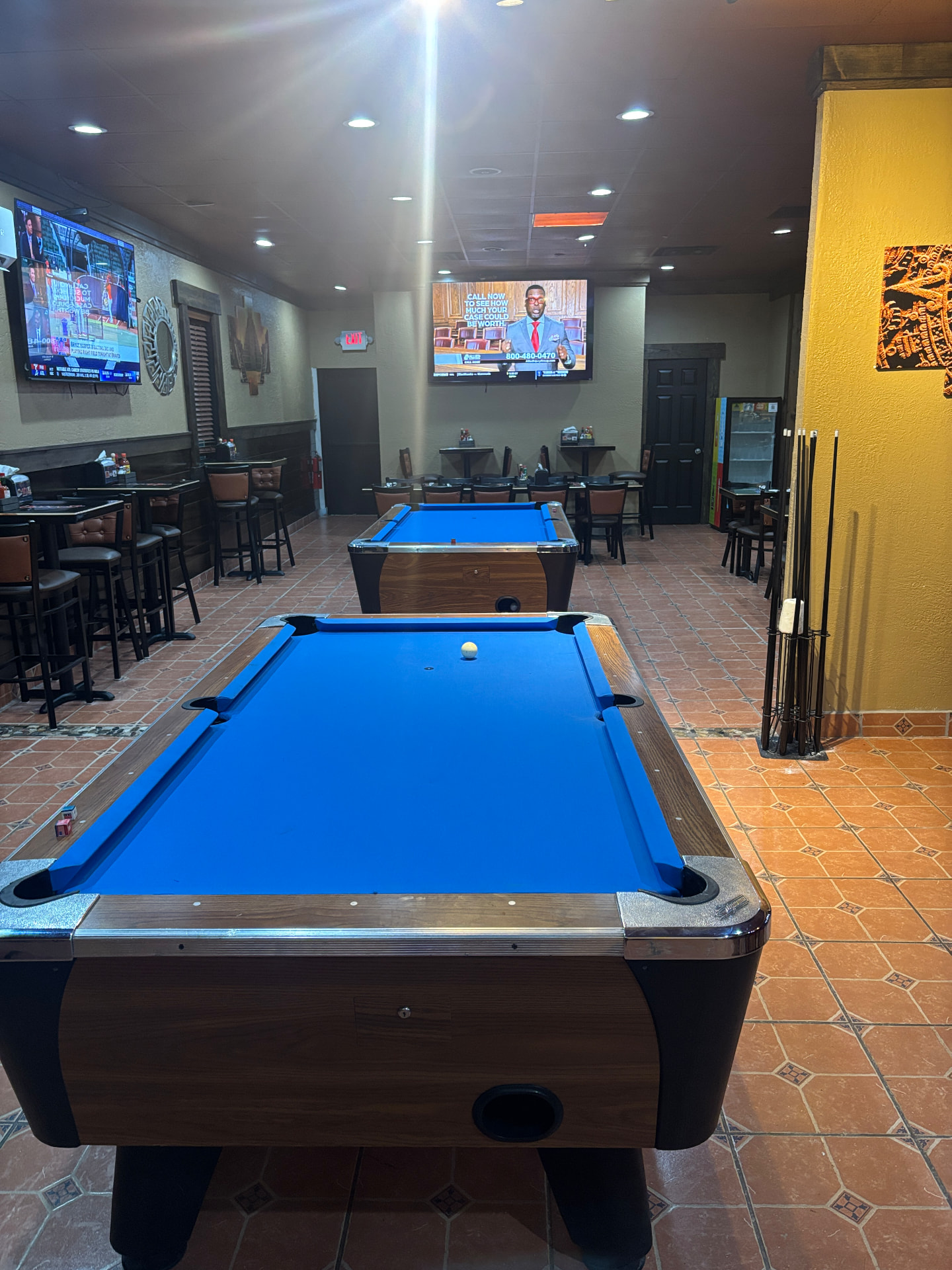 Dining room at Pikantes 2 with two blue pool tables, TVs and bar seating