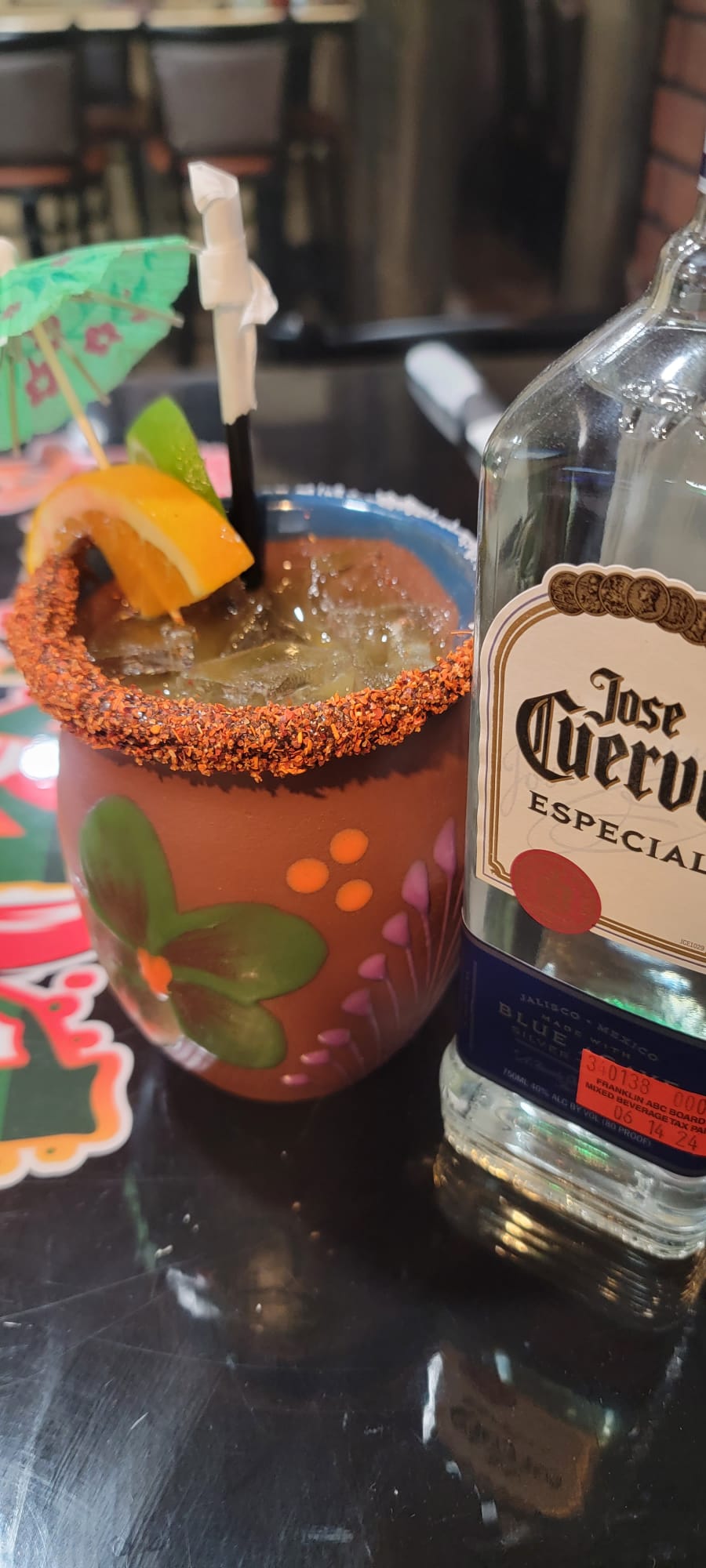 Cantarito served in a hand-painted clay cup with chili rim, orange and lime