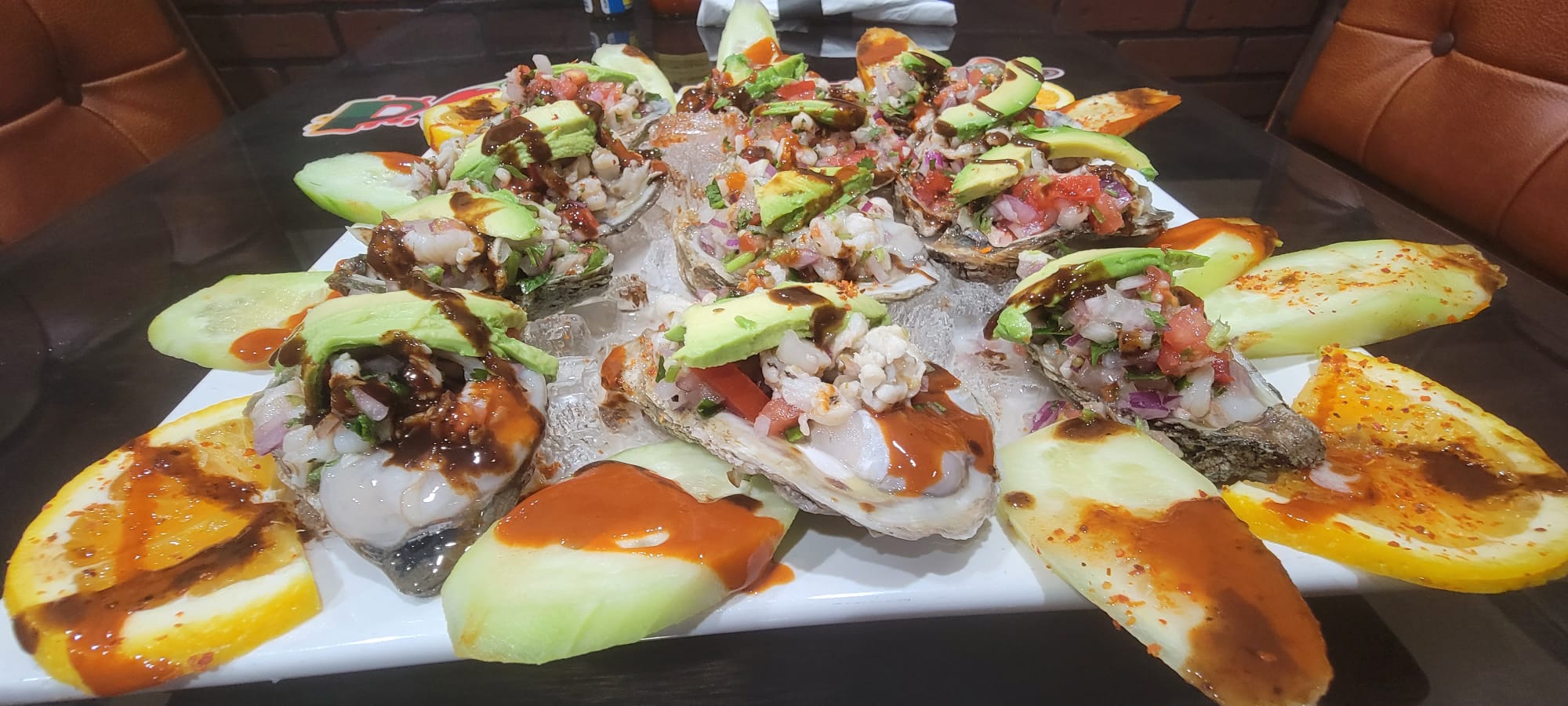 Platter of ostiones preparados on the half shell topped with shrimp, pico de gallo, avocado and chamoy