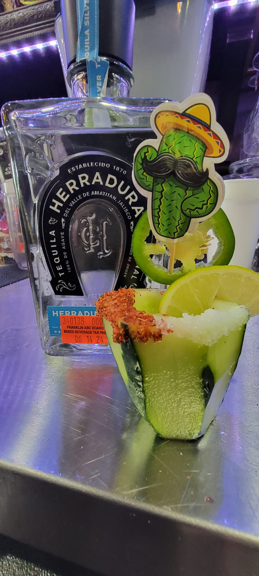 Tequila shot served inside a hollowed cucumber with chili rim, jalapeño and lime