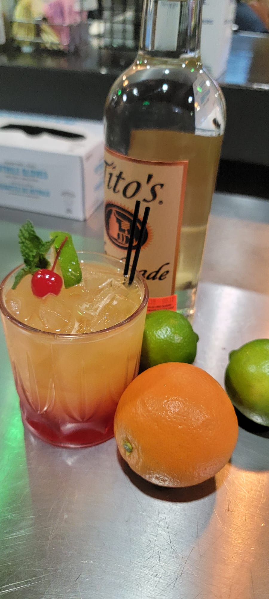 Citrus vodka cocktail on the rocks garnished with mint, lime and a cherry